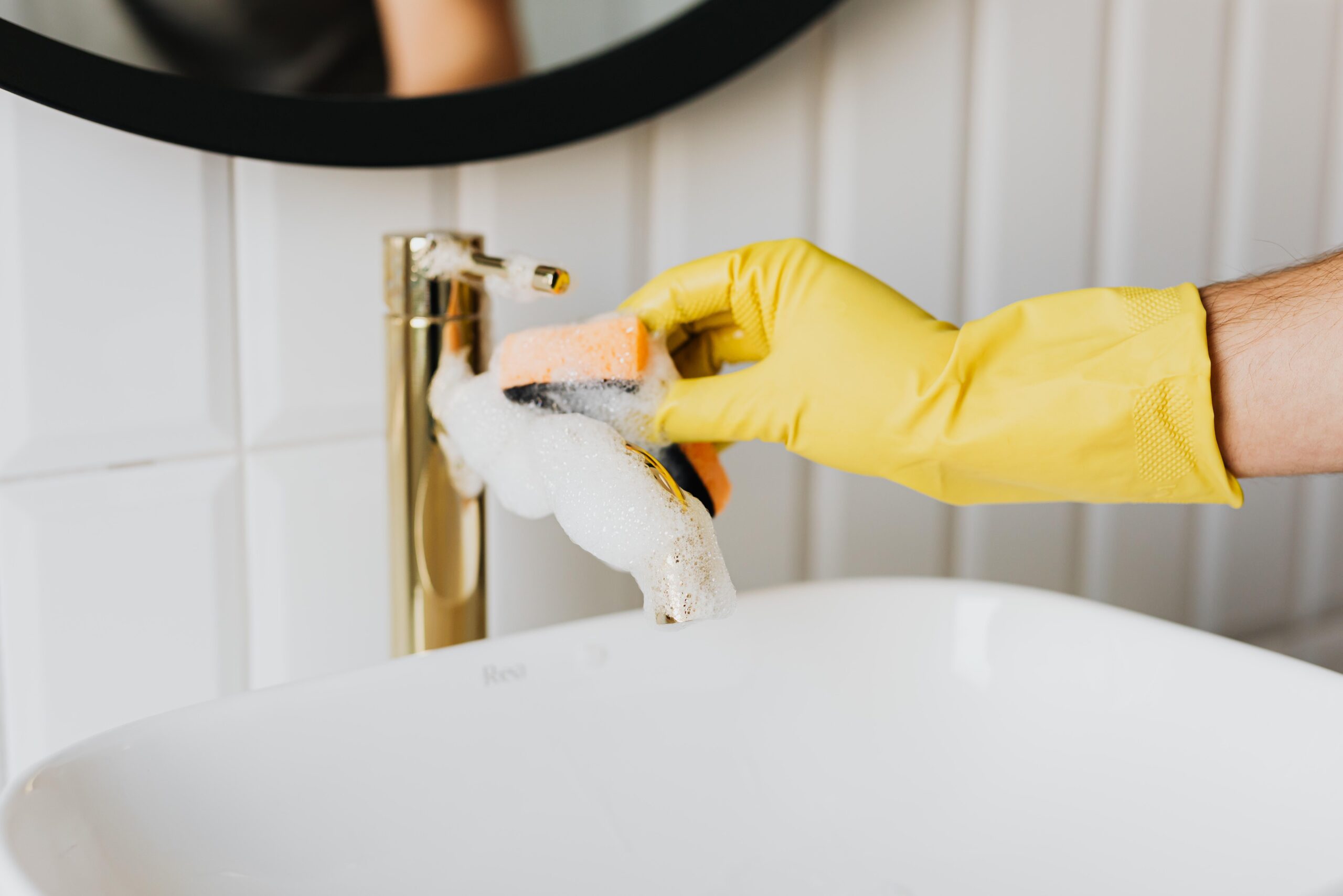 Détartrage d'un robinet doré avec des gants